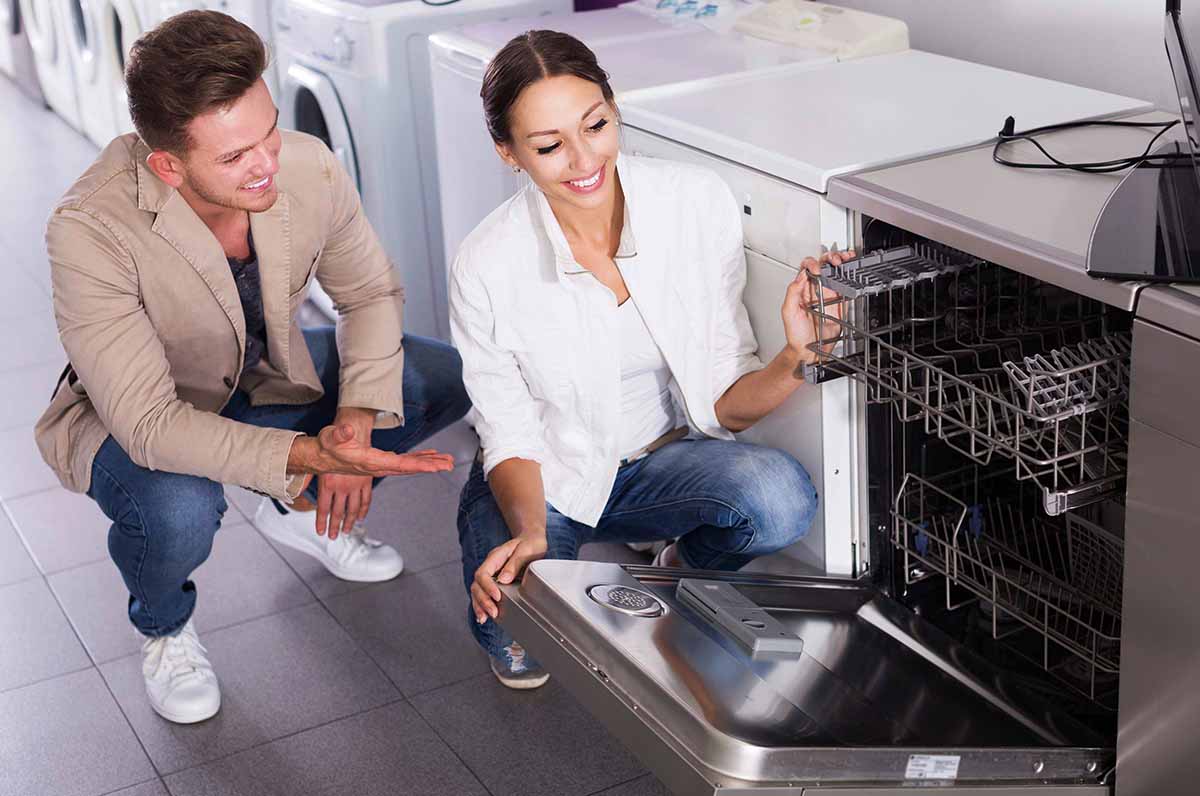 Casal a inspecionar interior de máquina de lavar loiça na loja